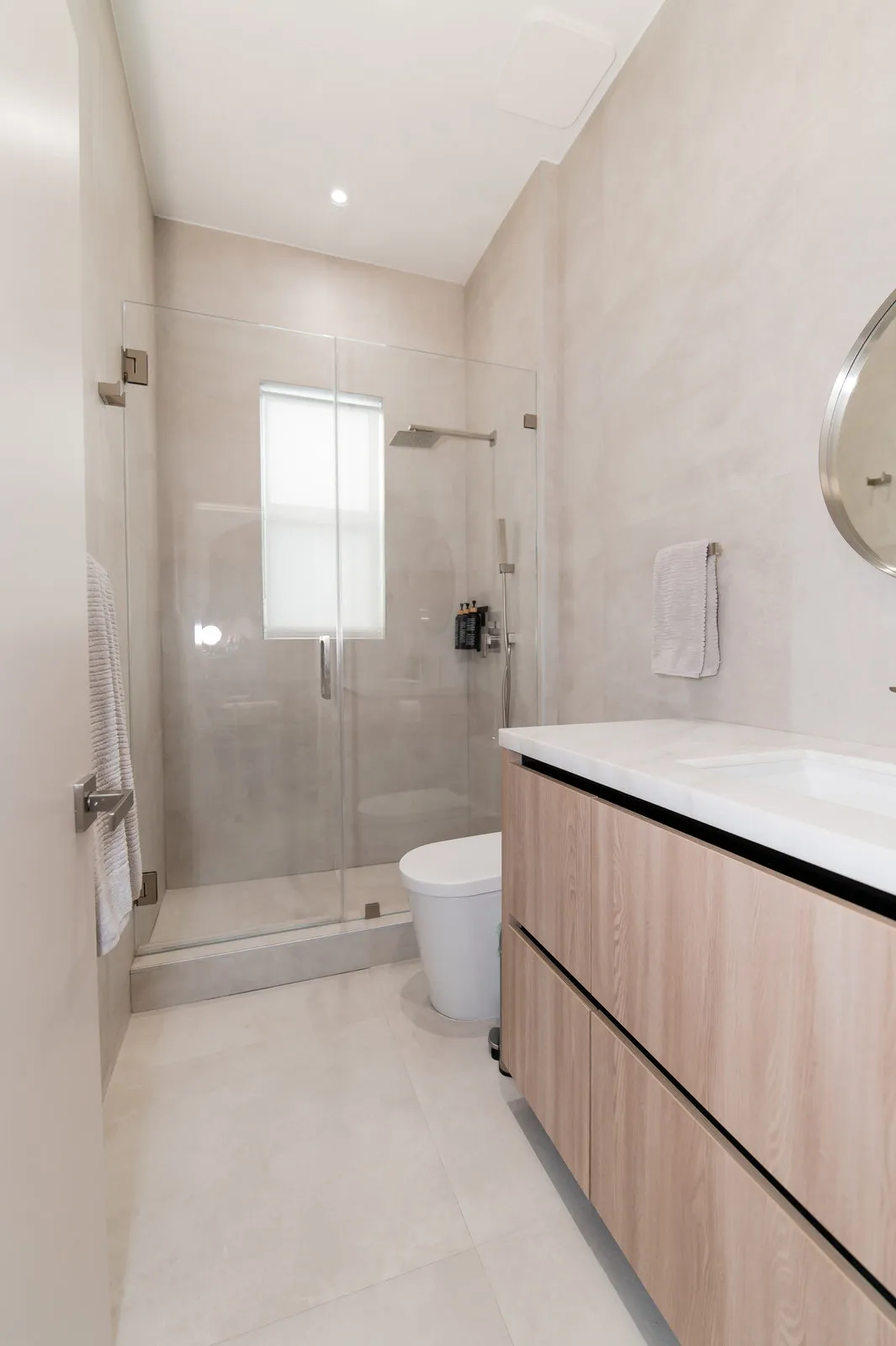 Walk-in shower in large-format grey stone with a black rain head, JH Residence guest bath