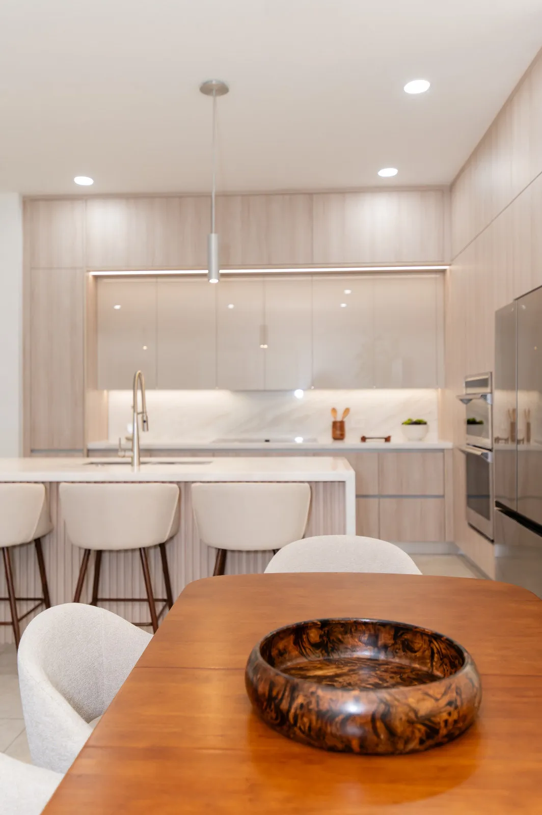 Pale oak kitchen run with integrated ovens and a marble island, JH Residence by DALOP Design