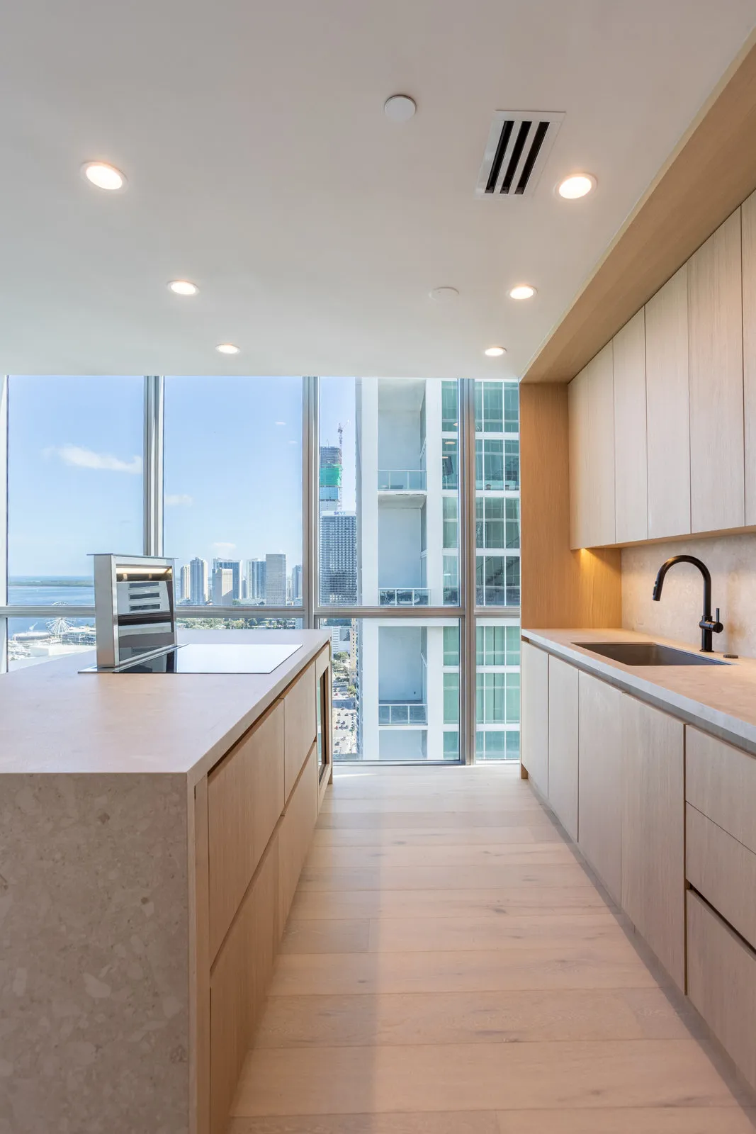 Oak kitchen with a marble island facing floor-to-ceiling windows over the bay, Marquis renovation