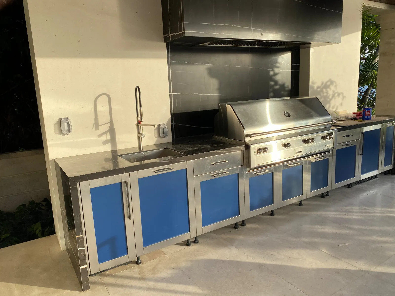 Stainless-steel outdoor kitchen with powder-coated blue doors on Star Island, designed by DALOP Design